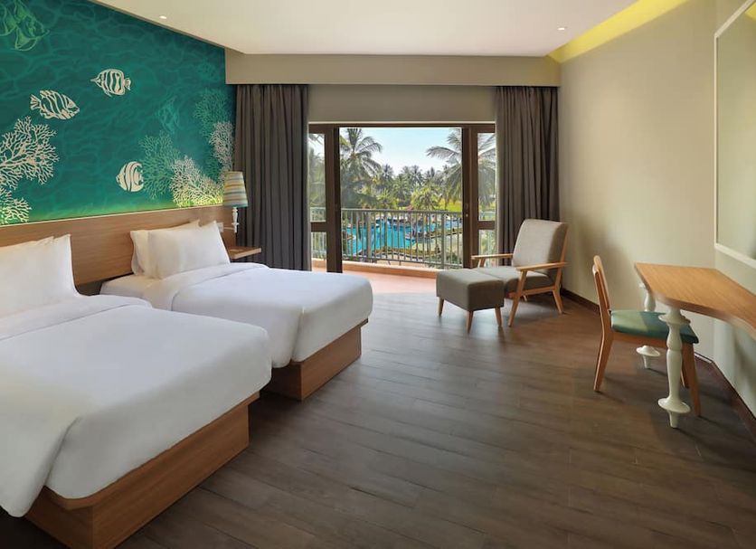 Manado Tateli Resort and Convention in Manado: twin beds, balcony view of palm trees and pool