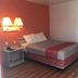 Motel 6 Lufkin guest room with queen bed, bedside lamp, and wood-look flooring
