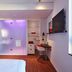 citizenM Rome Isola Tiberina room with bed, desk, wall-mounted TV and purple-lit shower area in Rome