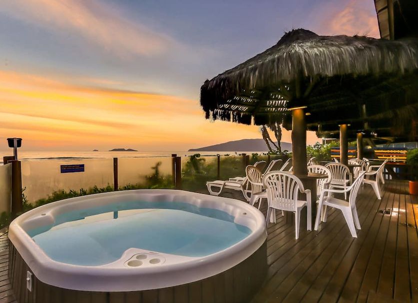 Costa Norte Ingleses Hotel in Florianopolis with a hot tub, outdoor dining area and sunset ocean view