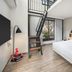 Moxy Bandung bedroom with loft ladder, large window, and queen bed in Bandung