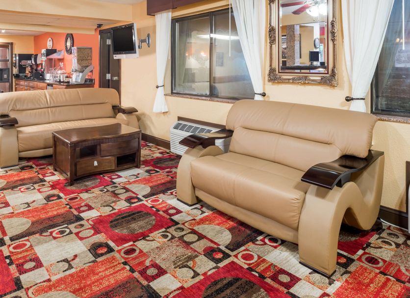 Super 8 by Wyndham Jacksonville lobby seating area with tan sofas and patterned carpet