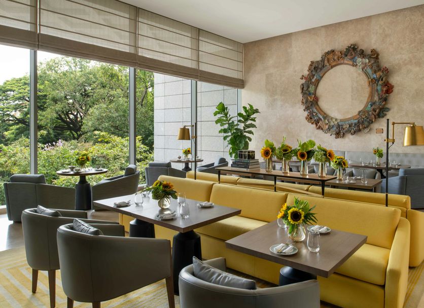 Four Seasons Hotel Bengaluru at Embassy One lounge with yellow sofa, tables, greenery and large windows
