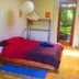 Sans Souci Inn in Pohara: cozy guest room with double bed, lamp, balcony door, and garden view