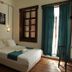 Olea Leya Hotel in Ayvalik bedroom with double bed, wood floors, and balcony doors with teal curtains