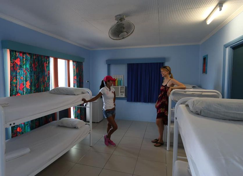 Caravella Backpackers in Cairns dorm room with bunk beds, colorful curtains, and two guests inside