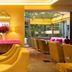 Hôtel Baume in Paris dining room with yellow chairs, pink console and glass-walled terrace
