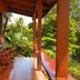 Aguila de Osa Rainforest Lodge in Agujitas de Drake with a wooden balcony rocking chair and lush tropical view