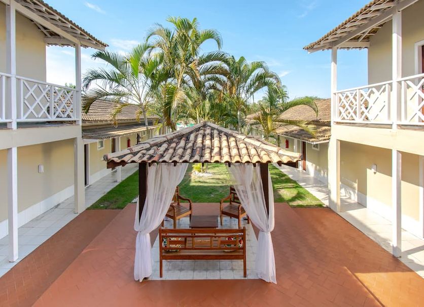 Pousada Casuarina Ferradura in Búzios with central cabana between palm-lined hotel buildings
