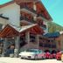 Hotel Beau Sejour in Etroubles with stone entrance, mountain setting, and parked sports cars
