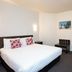 Distinction New Plymouth Hotel guest room with queen bed, wardrobe and wall-mounted TV in New Plymouth