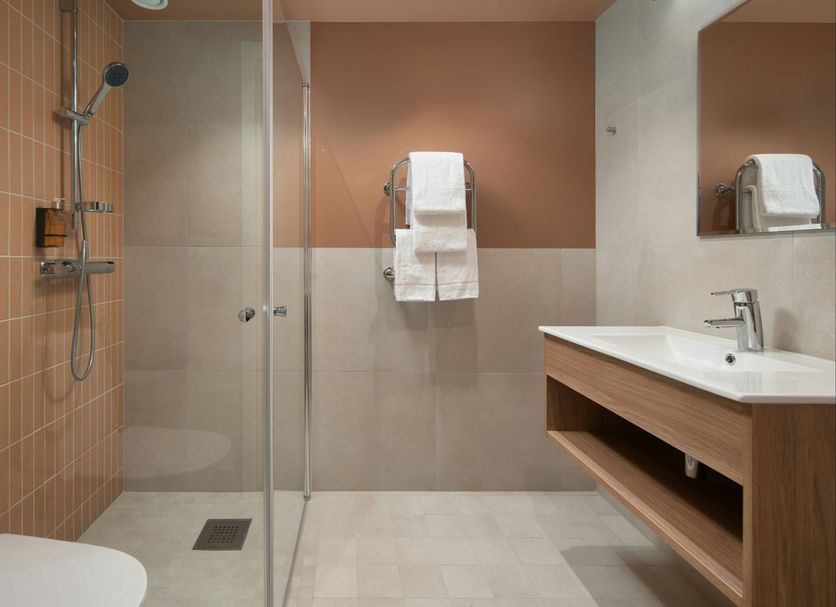 Sky Hotel Apartments Stockholm bathroom with walk-in shower, vanity sink, and towel rack