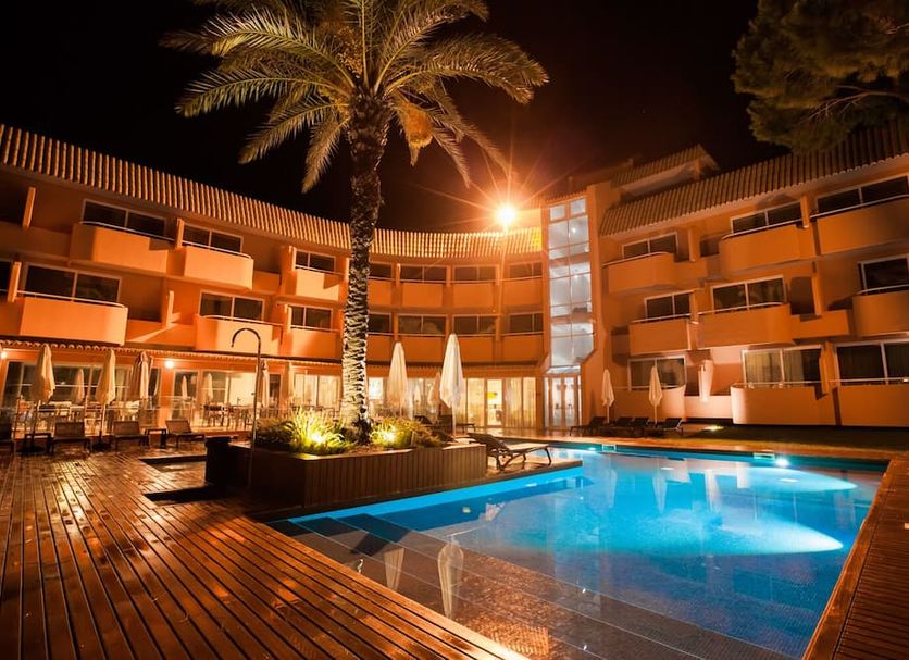 Vilamoura Garden Hotel in Vilamoura with illuminated outdoor pool, palm trees, and courtyard at night