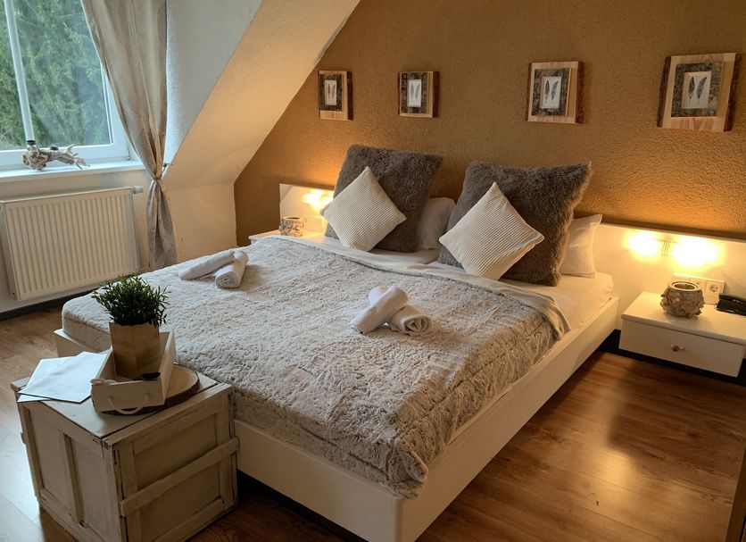 Berghotel Drei Brüder Höhe in Marienberg: cozy attic hotel room with double bed and bedside lamps