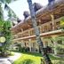 Mike's Dauin Dive Resort in Dauin with thatched-roof balconies, tropical garden, and palm-lined walkway