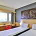 Ibis Goiania room in Goiânia with twin beds, window view and abstract headboard art