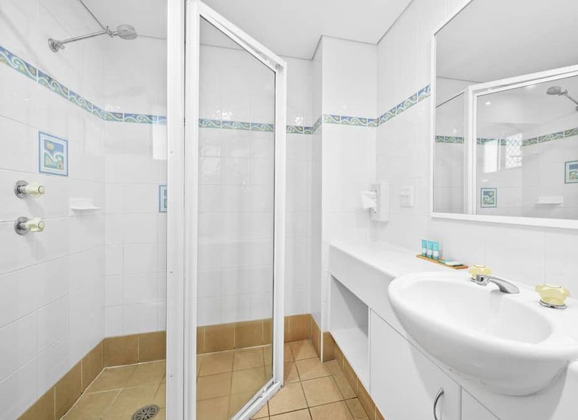 Macquarie Barracks Motor Inn in Port Macquarie bathroom with shower, sink, mirror and tiled floor