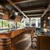 The Junto in Columbus bar with curved counter, leather stools and barrel table in a wood-paneled lounge