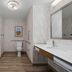 Hampton Inn Turlock bathroom with tub-shower, toilet, vanity, and wood-look flooring