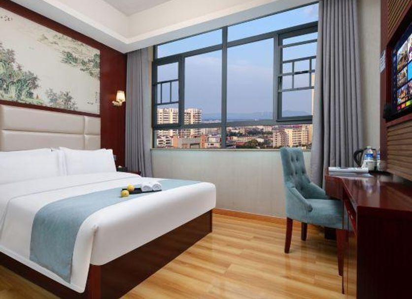 Wansheng Business Hotel in Changsha room with large window city view, bed and desk