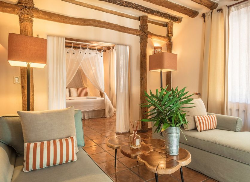 Ser Casasandra Boutique Hotel in Holbox: cozy suite with twin beds, rustic beams, and seating area