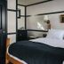 Brentwood Hotel, Saratoga Springs room with king bed, black bed runner, and wall-mounted lamps