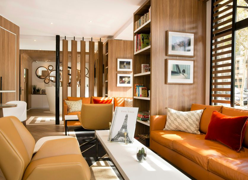 Hotel Eiffel Turenne in Paris lounge with tan sofa, armchair, coffee table, shelving and window light