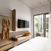 Basq House in Byron Bay guest room with balcony doors, wall-mounted TV, bench seating and hanging robes