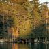 Motel Long Lake and Cottages on Long Lake, a lakeside cabin tucked among trees beside calm water.