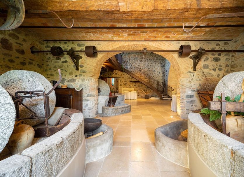 Tenuta Ciminata Greco in Rossano, rustic stone cellar lounge with arches, stairs, and wine barrels