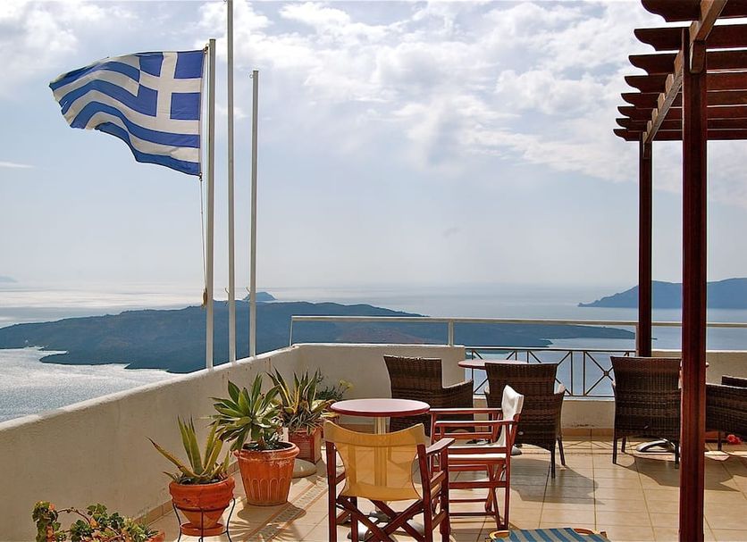 Theoxenia Caldera Hotel in Thera terrace with Greek flag and caldera sea view