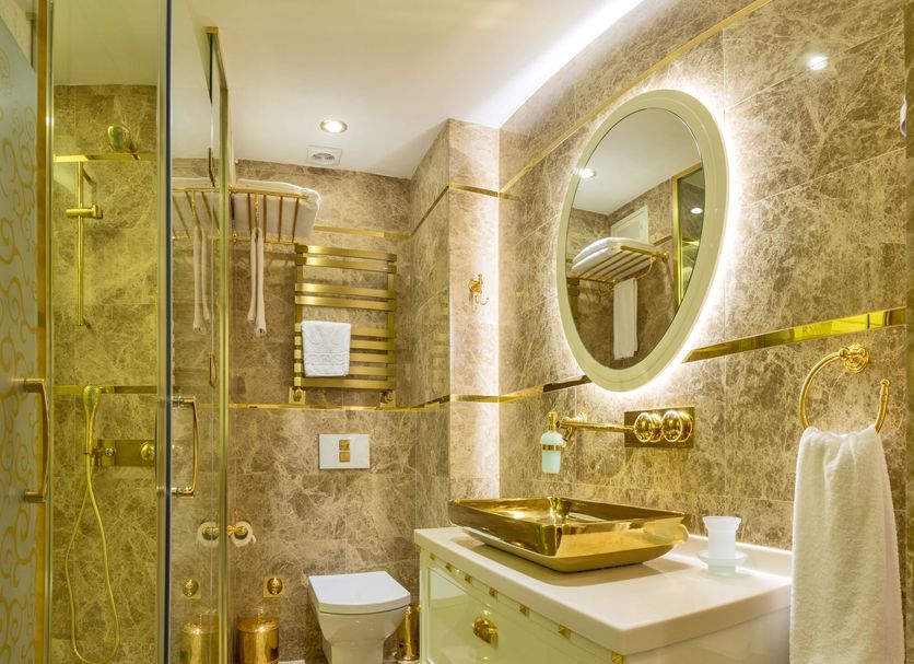 The Million Stone Hotel Istanbul bathroom with glass shower, gold sink, and oval mirror