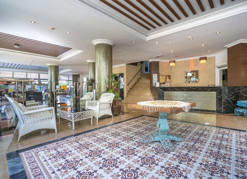Carmen Suite Hotel in Alanya lobby with patterned tile floor, seating area, stairs and front desk