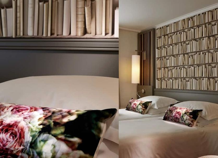 Hotel America Cannes guest room with twin beds, floral pillows and book-pattern wallpaper