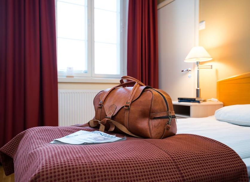 Hotelli Ville Tampere guest room with bed, leather duffel bag, lamp, and window with curtains