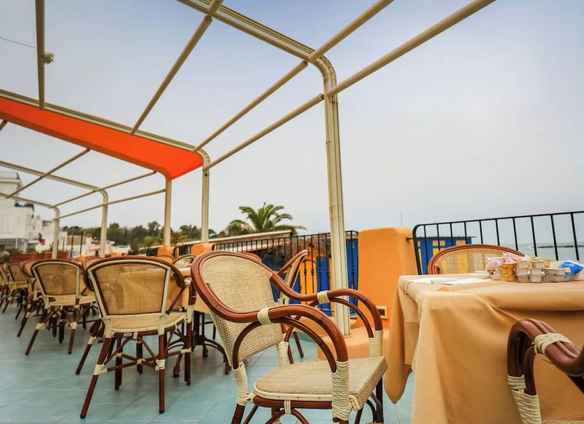 Hotel Rivamare in Ischia: seaside terrace dining area with wicker chairs and ocean view