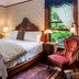 1899 Wright Inn & Carriage House in Asheville guest room with carved wood bed, floral wallpaper, and large windows