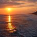 Sunset over the beach at Hotel Cocomar Beachfront Hotel in Parrita, with waves and palm-lined shore.