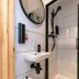 Easyhotel Paddington London bathroom with compact sink, round mirror, and black shower fittings