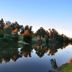 Countryman Motor Inn in Dubbo beside a calm river reflecting trees and sky at sunset