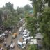 Hotel Pooja International in Nashik overlooks a busy tree-lined street with cars, rickshaws and pedestrians