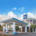Baymont by Wyndham Laurel exterior with covered entrance, blue sky, and landscaped trees in Laurel