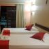 Hotel Pousada Cumbuco Gold room with two beds, balcony door and wall-mounted TV in Cumbuco