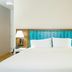 Hampton Inn Garden City guest room with king bed, white linens, wood headboard and bedside lamps