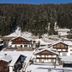 Residence Cesa Sassela in Ortisei with snow-covered chalet-style buildings on a forested mountainside
