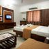 Sai Sangam Hotel in Shirdi guest room with twin beds, wall-mounted TV, and window curtains