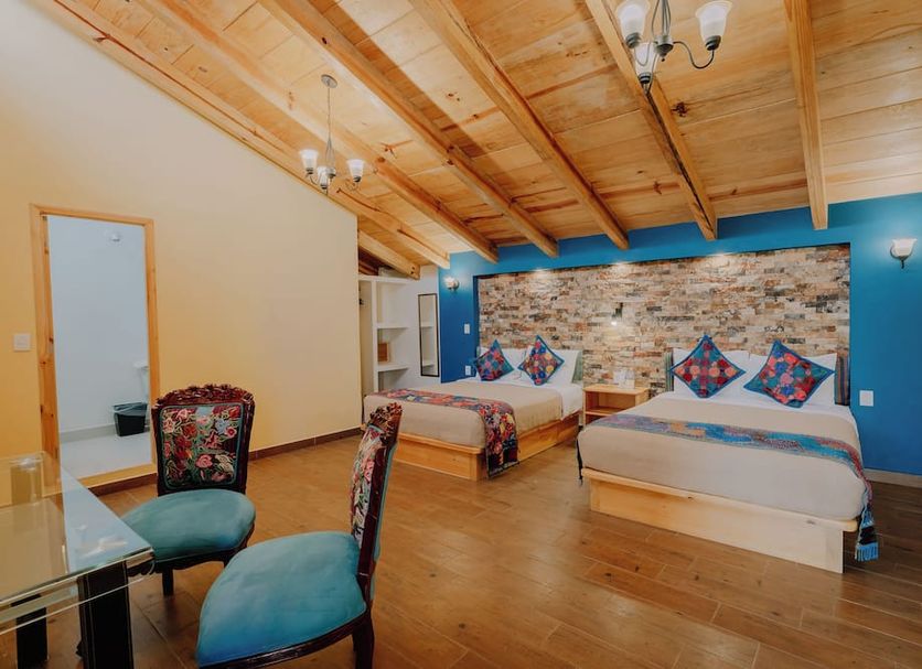 Hotel Cielo y Selva room with two beds, blue accent wall, and wood-beamed ceiling in San Cristóbal de las Casas