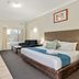 Sanctuary Resort Motor Inn in Coffs Harbour room with king bed, sofa, desk and balcony view