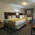 Baymont by Wyndham Chicago/Calumet City guest room with two beds, desk, and armchair in Calumet City