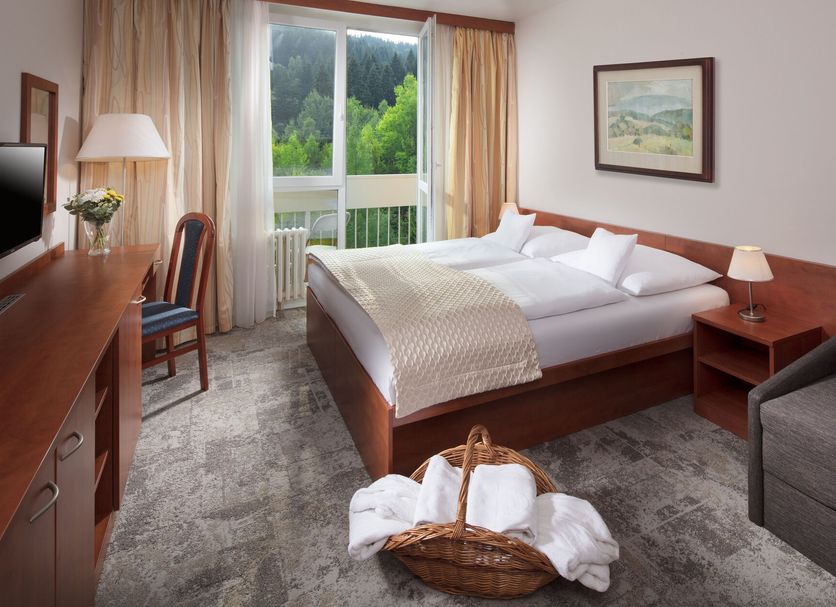 Pinia Hotel & Resort in Špindlerův Mlýn guest room with double bed, balcony doors, and forest view